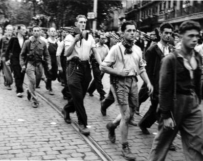 A group of men carrying guns walking down a street